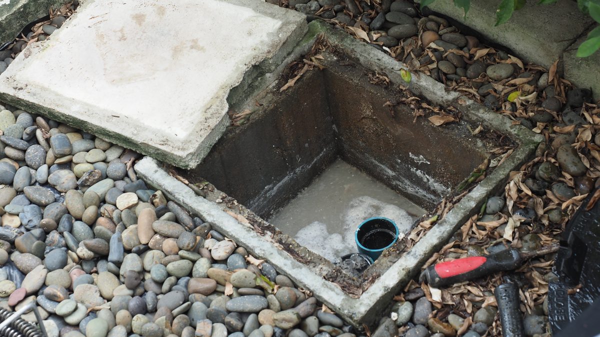 Grease trap lid lifted and the chamber being worked on