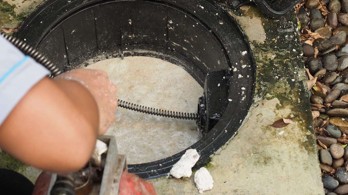 Open grease trap being cleared of blockage